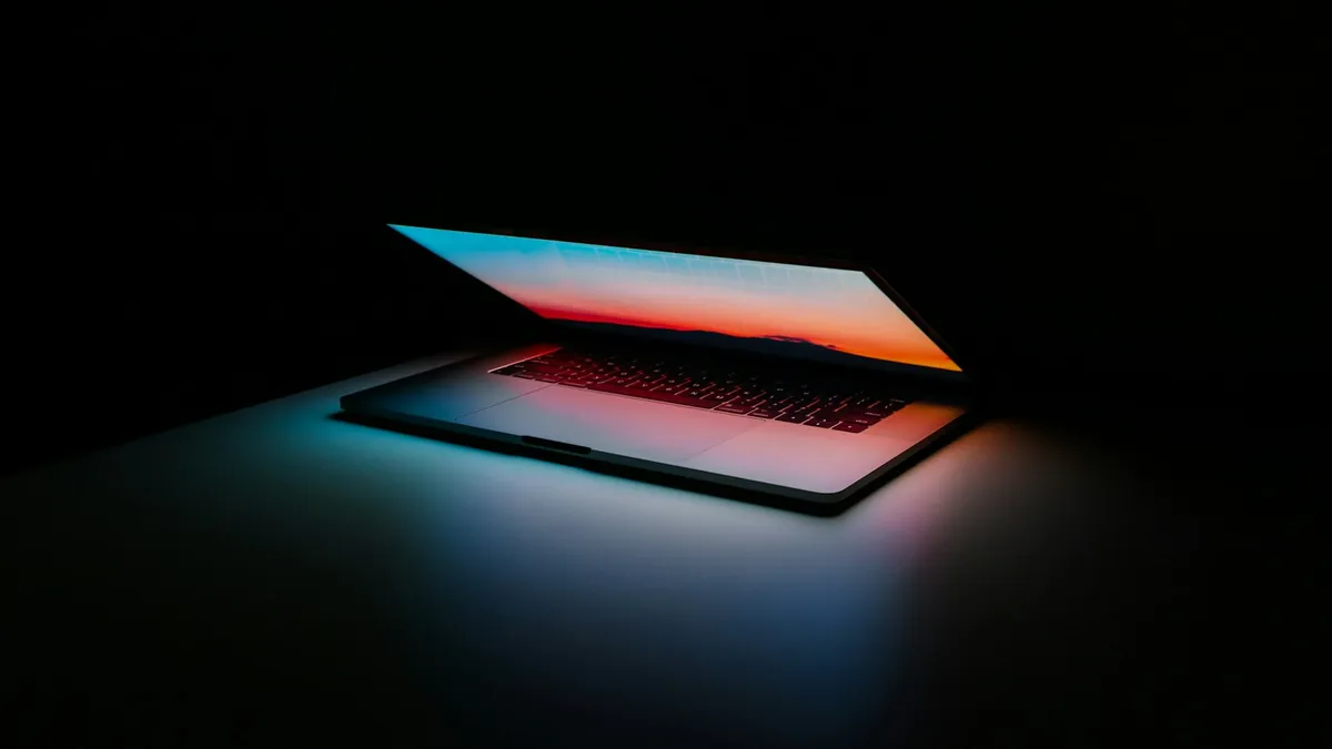Ordinateur portable entrouvert dans l'obscurité, son écran allumé éclairant le clavier