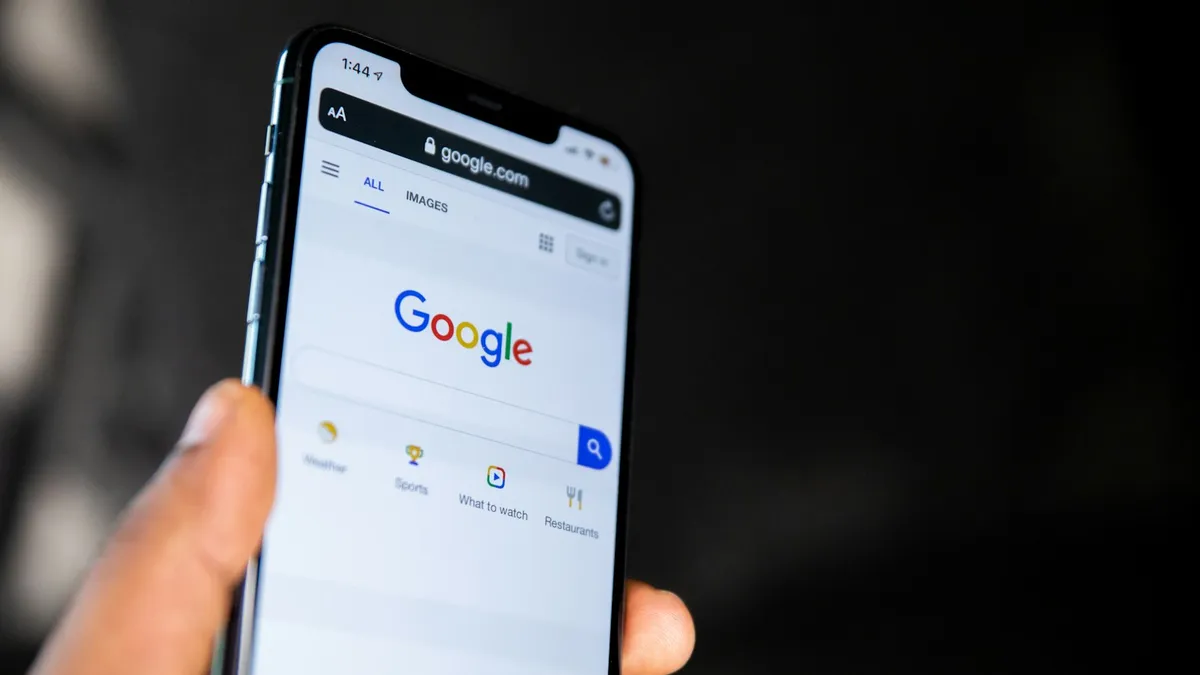Main tenant un smartphone ouvert sur la page d'accueil du moteur de recherche Google