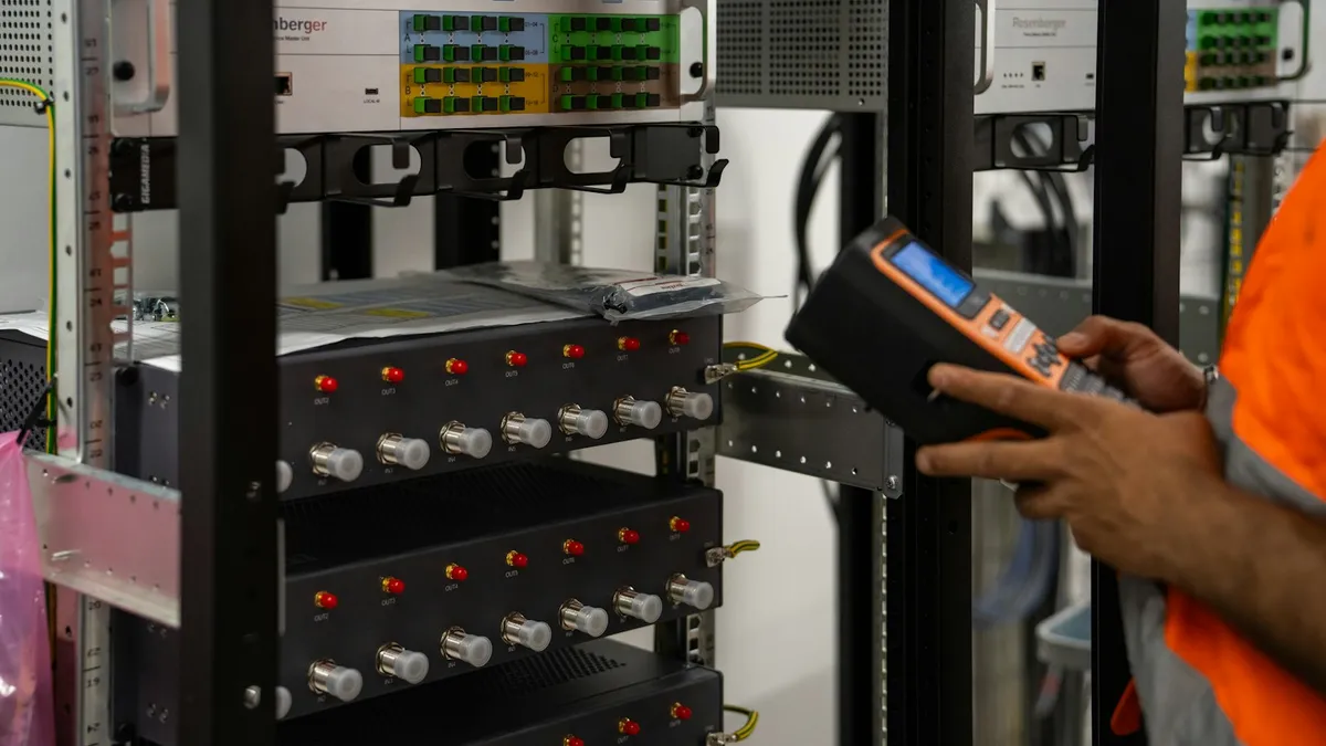 Technicien qui contrôle des baies de serveurs avec un appareil de diagnostic portatif à la main